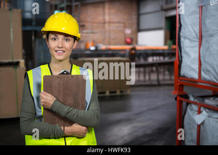 Portrait of young female worker holding clipboard in warehouse Stock Photo