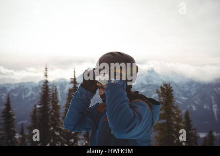 Man wearing helmet at mountain against sky during winter Stock Photo