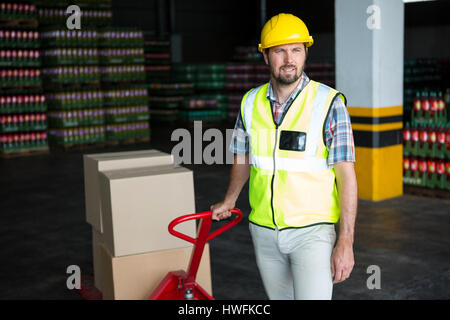 Young male worker pulling trolley in warehouse Stock Photo