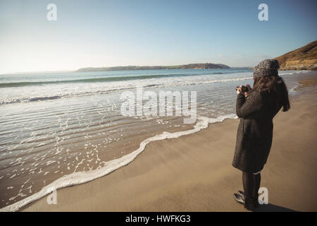 Woman taking photos on digital camera at beach during day Stock Photo