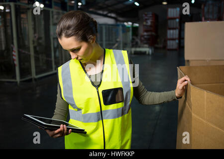 Serious female worker using tablet pc in warehouse Stock Photo