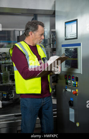 Manual worker analyzing machinery in factory Stock Photo