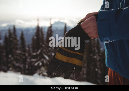 Midsection of man wearing gloves at mountain during winter Stock Photo
