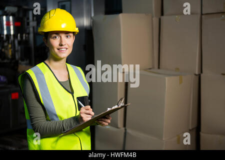 Portrait of female worker writing on clipboard in warehouse Stock Photo