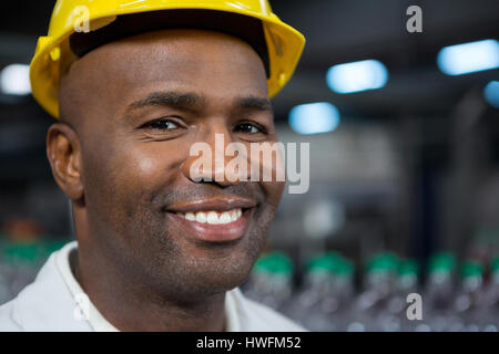 Close up portrait of smiling male worker wearing hard hat in warehouse Stock Photo