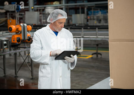 Serious male worker using digital tablet in cold drink factory Stock Photo