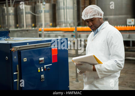 Serious male worker inspecting machines at juice factory Stock Photo