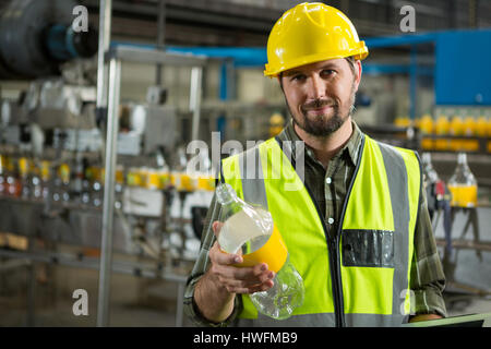 Portrait of confident male worker inspecting bottles in juice factory Stock Photo