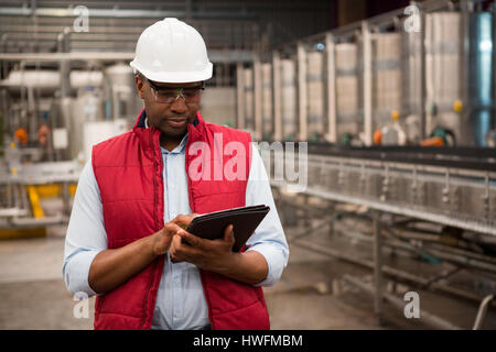Serious male employee using digital tablet in juice factory Stock Photo