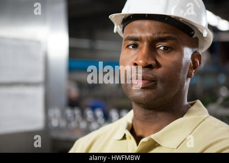 Close up of portrait serious male employee wearing hard hat in factory Stock Photo