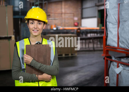 Portrait of young female worker holding clipboard in warehouse Stock Photo