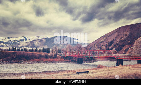 Red bridge in Rocky Mountains, color toning applied, Colorado, USA. Stock Photo