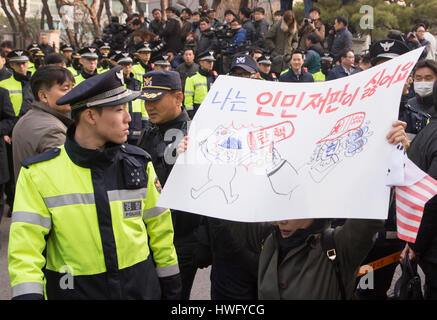 Seoul, South Korea. 21st Mar, 2017. Police officers stand guard as a supporter of ousted president Park Geun-Hye holds a sign in front of Park's home before she leaves to the Seoul Central District Prosecutors' Office to undergo prosecution questioning in Seoul, South Korea. The sign depicts South Korean Constitutional Court's ruling to oust Park Geun-hye as 'people's tribunal of communists'. Credit: Aflo Co. Ltd./Alamy Live News Stock Photo