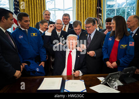 Washington DC, USA. 21st March 2017. U.S. President Donald J. Trump hands out pens after signing the NASA transition authorization act in the Oval Office of the White House in Washington, DC, USA, 21 March 2017. The bill boosts NASA's budget, much of which will be directed to the pursuit of a Mars mission. Credit: Jim LoScalzo/Pool via CNP /MediaPunch/Alamy Live News Stock Photo