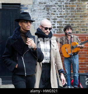 LONDON, UK - APRIL 22, 2016: Two fashionable men pass by street musicians Stock Photo