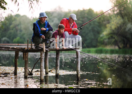 Two fishermen catch fish standing on the bridge Stock Photo