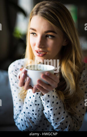 Portrait of young gorgeous female drinking tea and thoughtfully looking out of the coffee shop window while enjoying her leisure time alone, nice busi Stock Photo