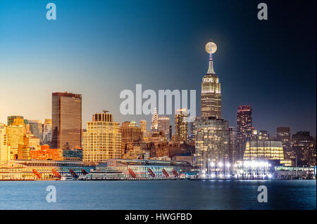 Composite day to night timelapse with the full moon rising above New York City skyline. Stock Photo