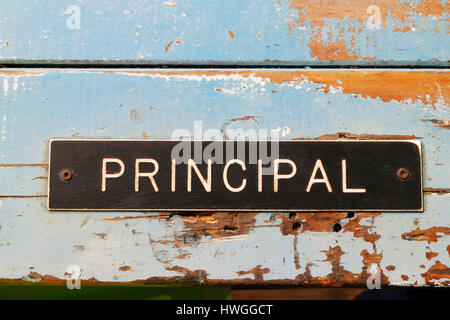 worn distressed school principal sign on old door Stock Photo