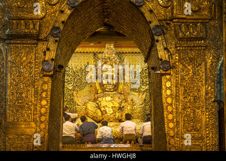 Saint golden Buddha in Mahamuni Pagoda, locals praying, Mandalay, Myanmar Stock Photo
