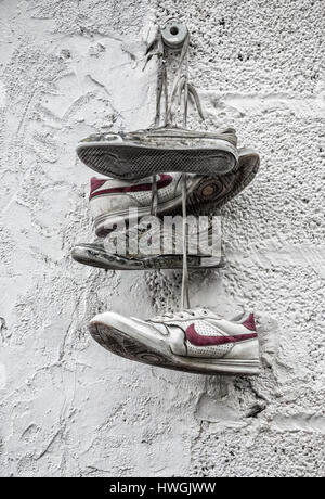 Old Nike trainers hanging from exterior wall. Stock Photo