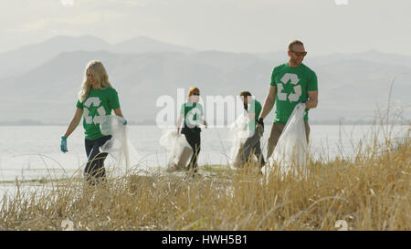 Volunteers collecting recycling and trash garbage on remote grassy lake shore Stock Photo