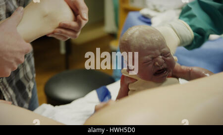 Selective focus view of doctor helping mother birth crying newborn baby in hospital Stock Photo