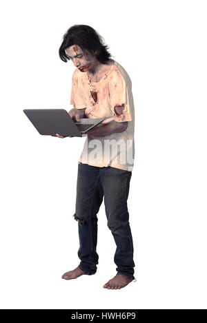 Creepy asian male zombie typing with laptop isolated over white background Stock Photo