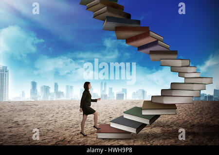 Business person step up flying book that look like stair. Career and education concept Stock Photo