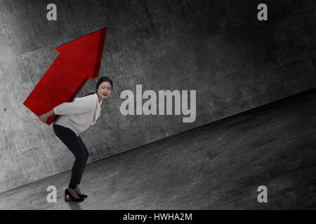 Asian business woman lifting heavy arrow. Business challenge concept Stock Photo