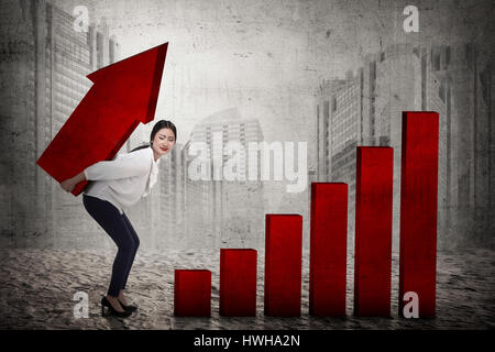 Asian business woman lifting heavy arrow. Business challenge concept Stock Photo