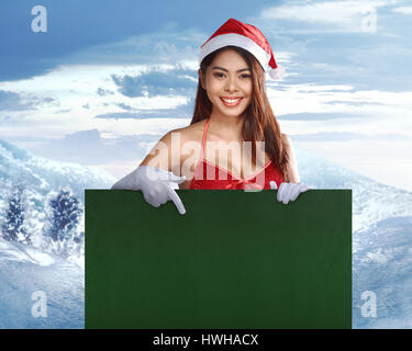 Pretty asian santa claus woman holding a green billboard for copyspace Stock Photo
