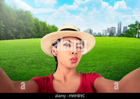 Asian woman doing selfie with duck face on the city park Stock Photo