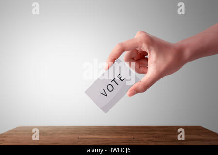 Person hand giving his vote in a ballot box against white background Stock Photo