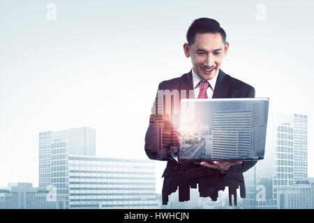 Double exposure of asian business man typing with laptop combined with building Stock Photo