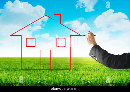 Business man drawing house on the meadow with blue sky background Stock Photo