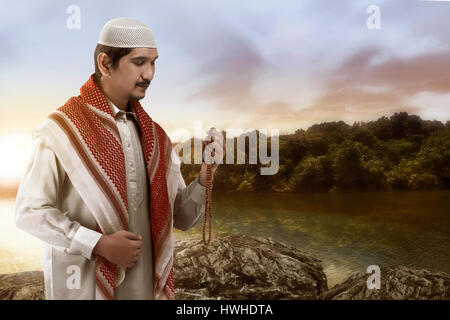 Young muslim man praying with lake background Stock Photo