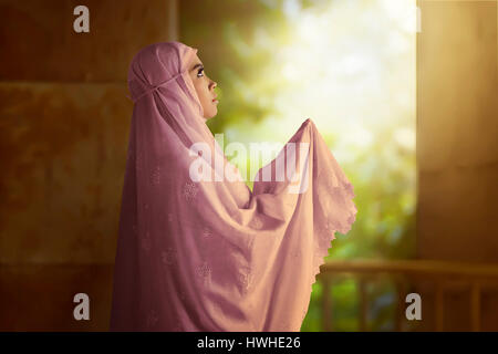 Asian muslim woman wearing  pink veil. she pray to god with two hand. Stock Photo