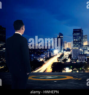 Business man standing on rooftop helipad. Looking at the city. Business success concept Stock Photo