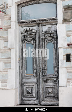 Olde grey vintage double-leaf door made of carved decorations painted in white wood framed with biege stones in Rostov-on-Don Russia Stock Photo