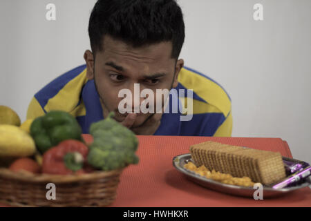 Man confused between healthy food and junk food Stock Photo