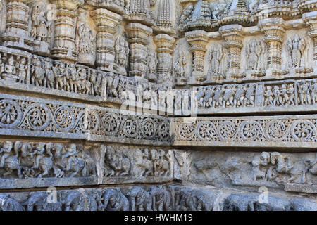 Stone sculptures of deities, panel below depicting stories from puranas and band of foliage, Chennakesava Temple, Hoysala Architecture exterior wall,  Stock Photo