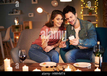 Couple having sushi meal and using cell phone Stock Photo