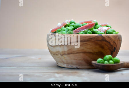 DISH OF WOOD FULL OF PEAS WITH HAM ON TABLE RUSTIC Stock Photo