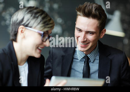 Cheerful young colleagues sitting in office and having good time while working together on joint project, head and shoulders portrait Stock Photo