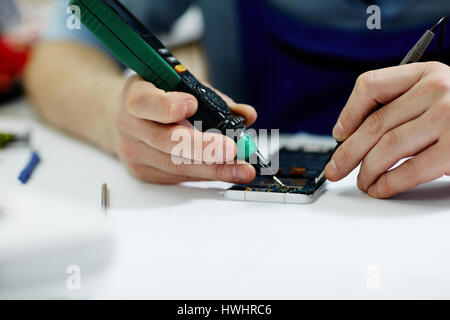 Closeup shot of male hands working on disassembling circuit board in mobile phone device Stock Photo
