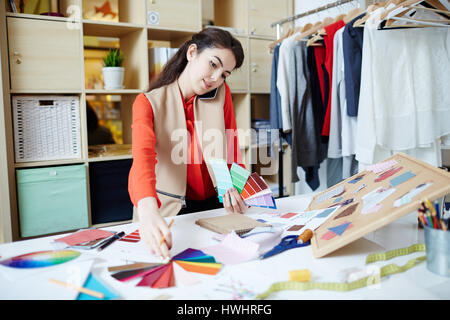 Confident designer speaking on mobile phone while choosing colors from palette Stock Photo
