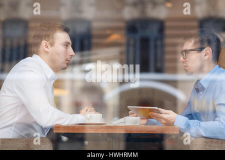Serious professionals sitting by table in cafe and discussing new data or ideas Stock Photo
