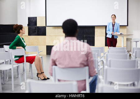 Team of co-workers or students consulting in conference-hall Stock Photo