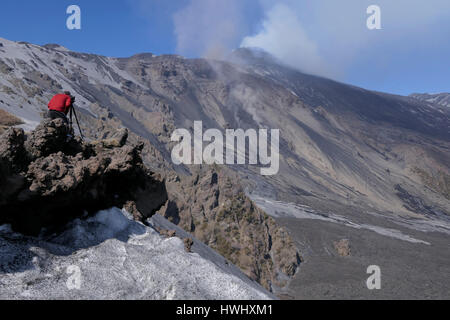 Photographer taking pictures and shooting video of the March 2017 eruption on Mount Etna in Sicily, southern Italy, the largest active volcano in Euro Stock Photo